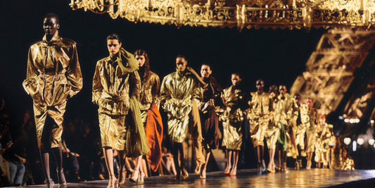 Saint Laurent runway at night beneath the lit Eiffel Tower, models in gold metallic looks