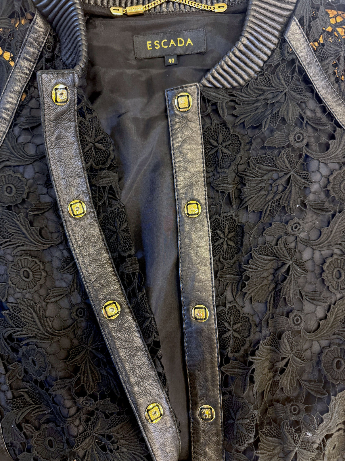 Brandsamsara Escada black leather jacket featuring intricate floral lace panels and gold-tone button detailing.