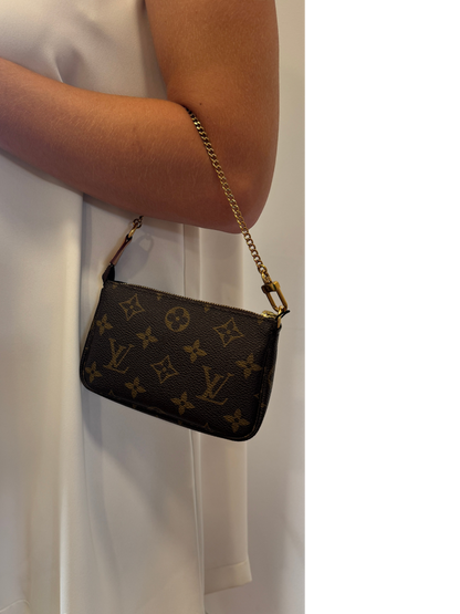Brandsamsara Louis Vuitton Monogram Mini Pochette handbag in brown leather with a gold chain strap worn on the arm